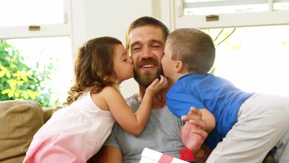 Children giving a kiss to their father