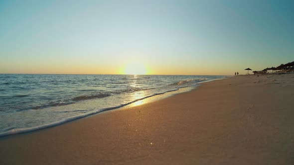 Sunset on the beach, shining golden waves