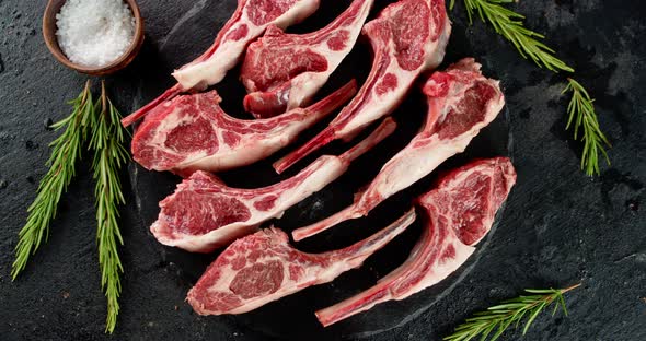 Sliced Raw Rack of Lamb with Rosemary Rotates on the Table. 