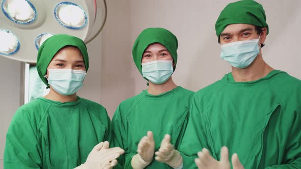 Group of Asian doctors and nurse working in Hospital operating room and clap hands after success.