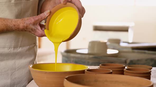 Mid-section of female potter pouring paint into bowl