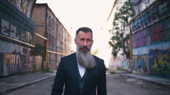 Handsome Bearded Mature Man in Suit Walking Outdoors in City with Graffiti Background Slow Motion