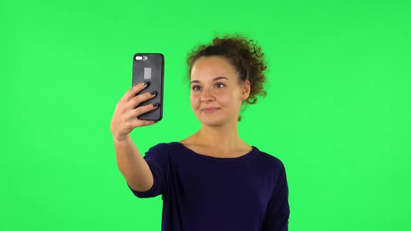 Portrait of Curly Woman Smiling Woman Texting on Her Phone . Green Screen