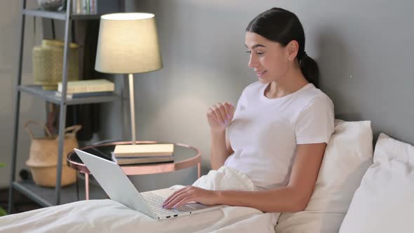 Video Chat on Laptop By Young Latin Woman in Bed