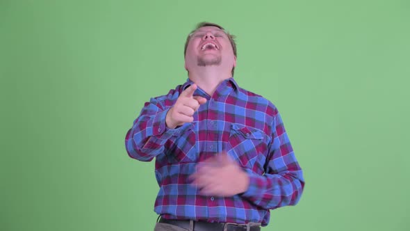 Happy Overweight Bearded Hipster Man Laughing and Pointing at Camera