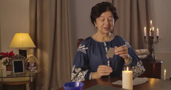 Nice Brunette Caucasian Woman Taking Out Cards From Card Deck Lying on the Table