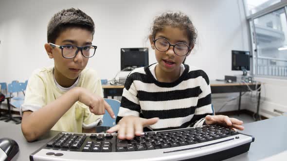 Schoolkids Sitting at Table and Using Computer