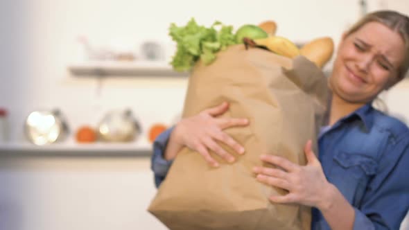 Young Woman Carrying Heavy Paper Bag With Products From Shop, Needs Delivery