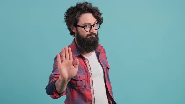 Young Man with Big Beard with Bad Attitude Making Stop Sign with Hand.