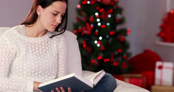 Pretty brunette reading book at christmas time