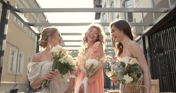 Three Hapy Ladies with Bouquets Posing in the City
