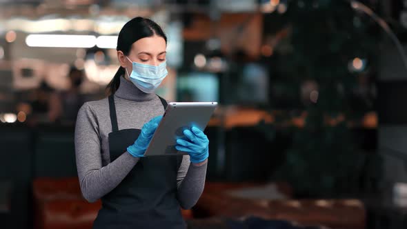 Female Waitress in Protective Face Mask and Gloves Use Tablet Digital Menu