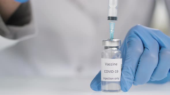 Unrecognizable Doctor Filling Syringe with Covid-19 Vaccine