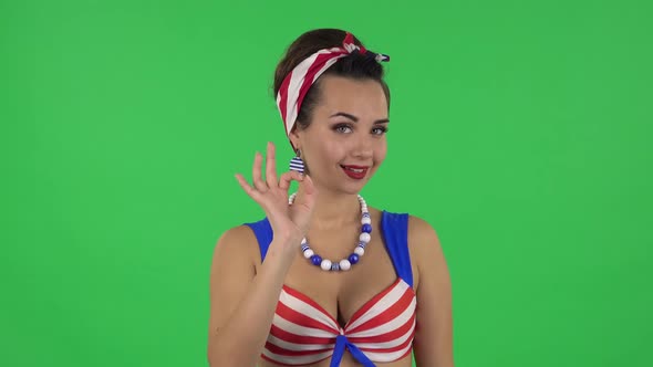 Portrait of Beautiful Girl in a Swimsuit Is Making Sign Ok. Green Screen