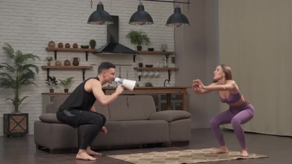 Low angle of personal coach shouting to young woman while she doing squats the rope