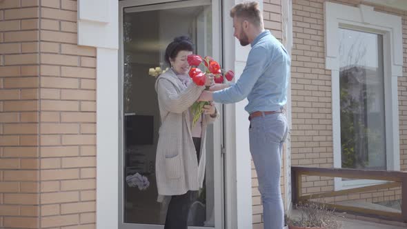 Man Bringing Bouquet of Tulips To Grandma The Bearded Man Hugging His Granny