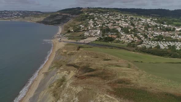 Dorset coast aerial looking west over Charmouth in the foreground and Lyme Regis in the distance. Am