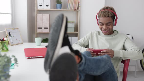 Smiling Addicted Young Latin Teenage Man Playing Video Games on Mobile Phone App