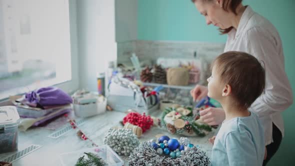 A Girl and a Child Collect a Christmas Wreath Together