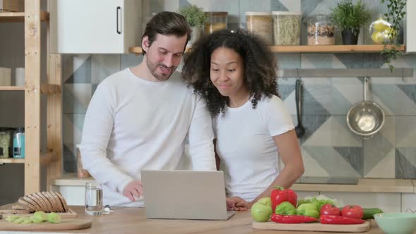 Mixed Race Couple Doing Video Call on Laptop in Kitchen