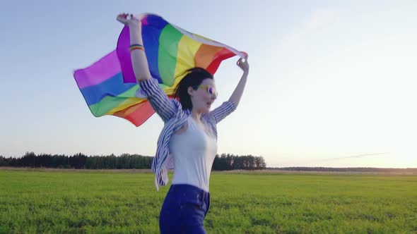 Young Attractive Woman Runs Across Field with LGBT Flag Slow Mo