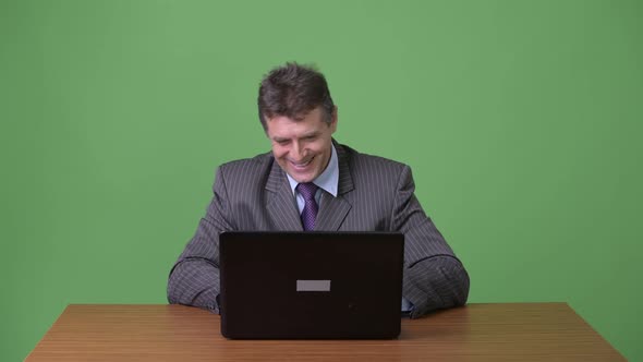 Mature Handsome Businessman Against Green Background