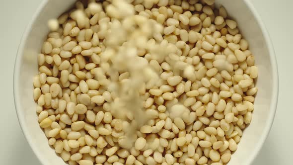 Pine Nuts Falling Into A White Bowl