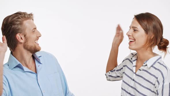 Young Caucasian Couple Gives High Five with One Hand to Each Other and Smiling on White Background