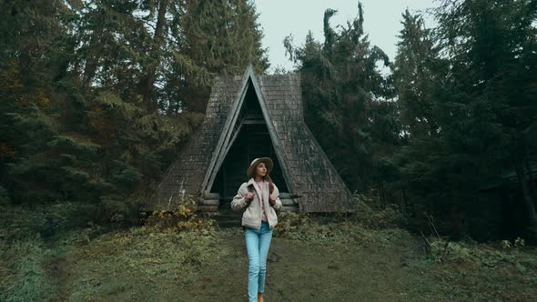 Hiker Woman in Casual Wear and Hat with Backpack Hiking in Green Fall Woods with Pines