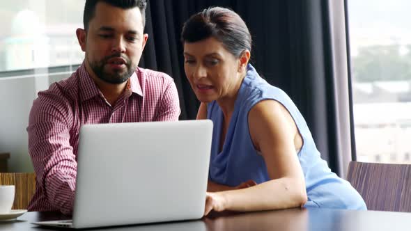 Business executives discussing over laptop