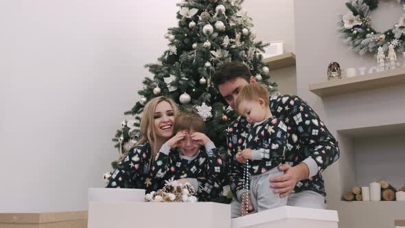 Family of Four Unwrapping Christmas Gifts Near Christmas Tree