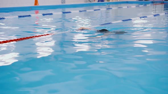 Swimming Lessons for Children in the Pool - Beautiful Fair-skinned Girl Swims in the Water