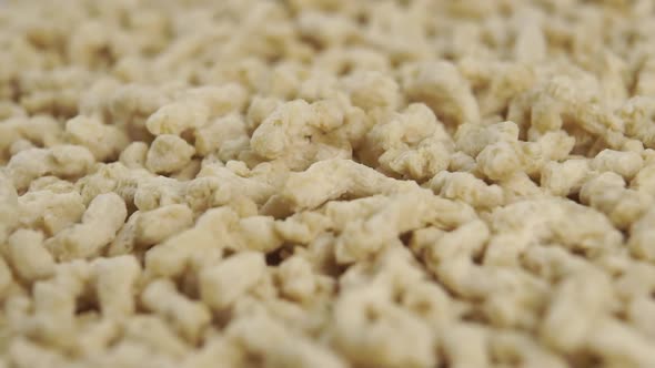 Texturized soy granules fall into a pile in slow motion