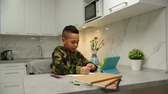 Preteen Schoolboy Doing Homework with Digital Tablet Internet Indoors