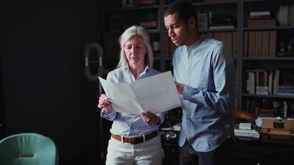 Two buiness people looking at a blueprint in the office