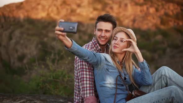 Cute Young Pair Making Selfie with Mobile Phone Smiling Showing Peace and Love