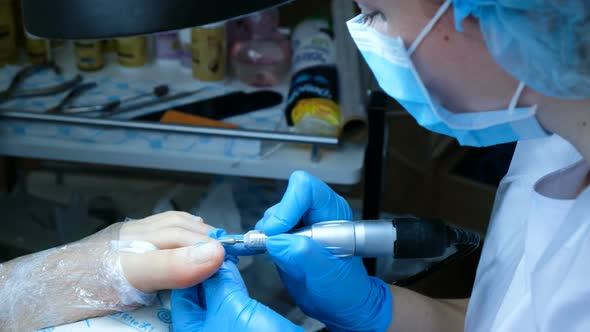 Woman in Gloves Does Pedicure and Handles Toenails Cuticle