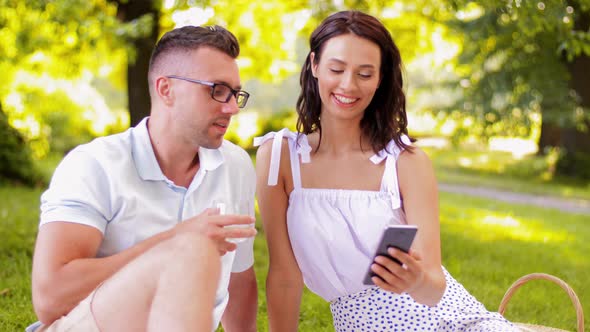 Happy Couple with Smartphone at Picnic in Park