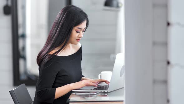 Side View Adorable Young Asian Female Freelancer Smiling and Working Using Laptop Pc