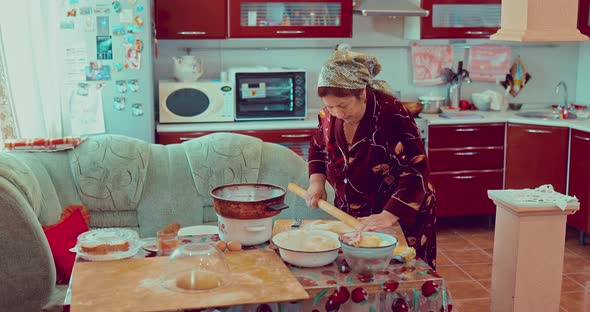 Elderly Woman Rolls Dough in the Kitchen Preparing a Pie