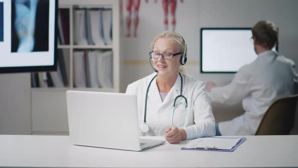 Mature Doctor in Headset Talking to Patient Online on Video Chat