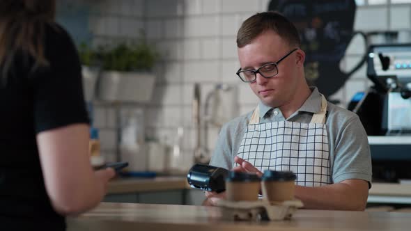 Caucasian man with down syndrome as a waiter accepting contactless payment in the cafe. Shot with RE