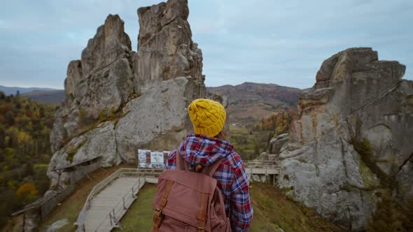 Camera Moves Around Woman Hiker with Casual Retro Backpack Standing on Top of a Cliff and Enjoying