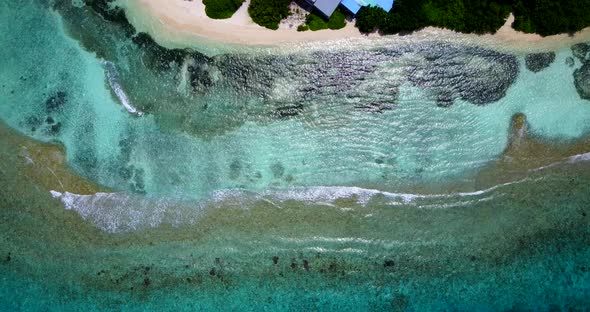 Daytime overhead travel shot of a sandy white paradise beach and aqua blue ocean background in hi res