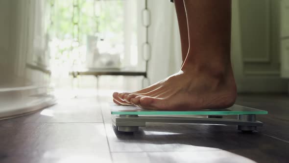 Woman checking her weight on weighing scale at home 4k