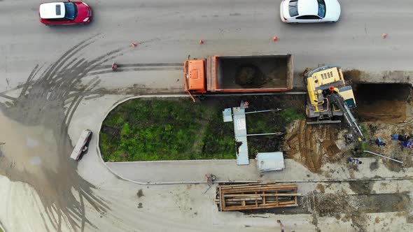 Excavator loads KAMAZ. Repair the road from a height.