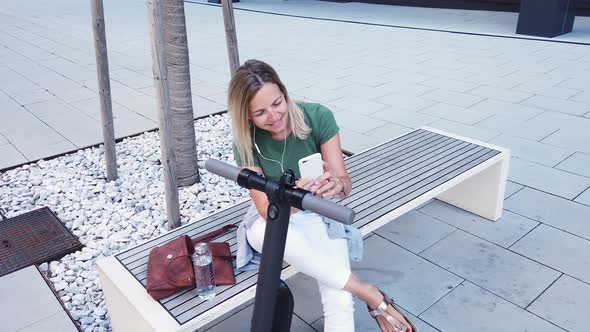 Woman sitting on bench in city having video call over smartphone