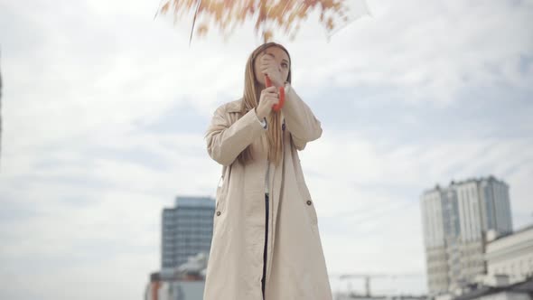 Bottom View of Charming Young Woman Opening Beautiful Umbrella and Looking Around. Portrait of Happy