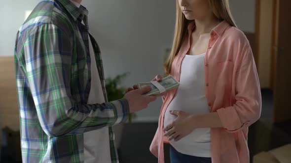 Young Man Giving Lot of Money to Pregnant Girlfriend, Paying Off From Child