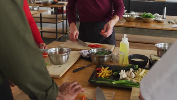 Caucasian female chef teaching diverse group wearing face masks